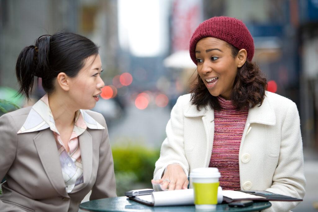 Two business women having a casual meeting or discussion in the city.