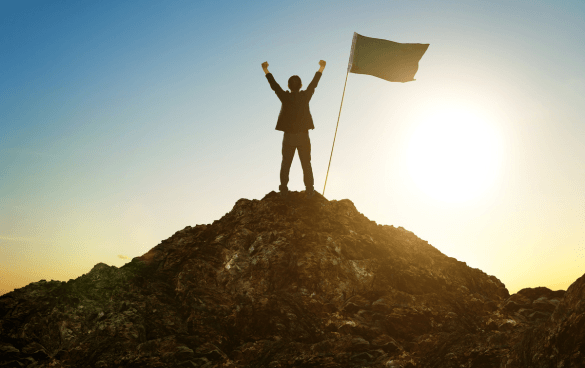 Man standing at the top of a mountain with a flag